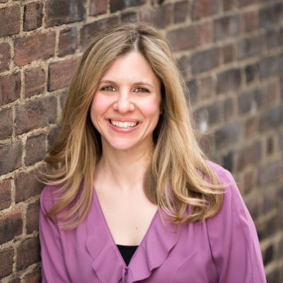 Mary Clavieres smiling beside a brick wall